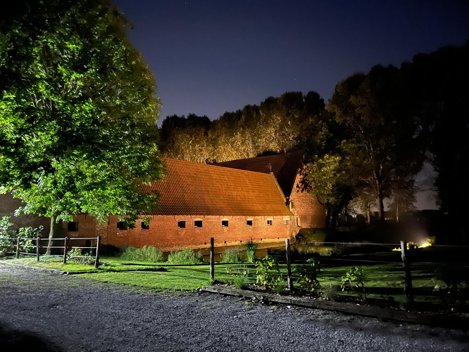 La longère en briques illuminée de nuit, vue depuis l'allée